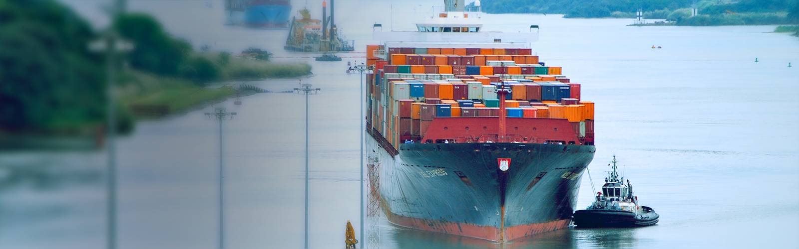 Buque portacontenedores avanzando por el Canal de Panamá con un remolcador