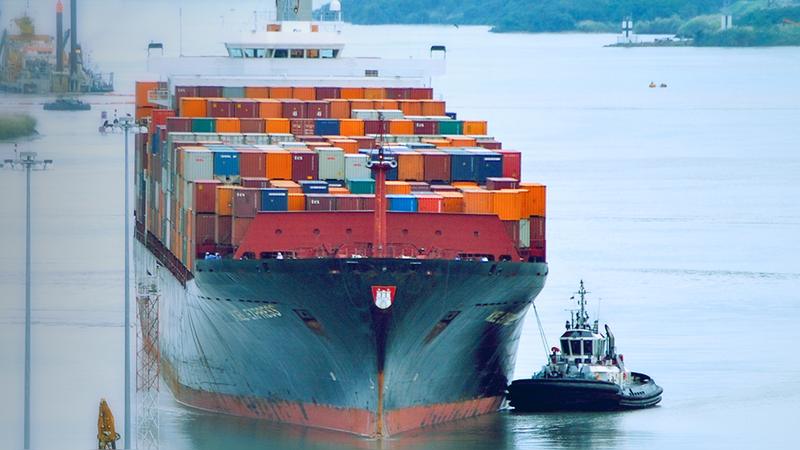 Buque portacontenedores avanzando por el Canal de Panamá con un remolcador